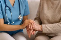 Sjuksköterska håller en äldre persons hand